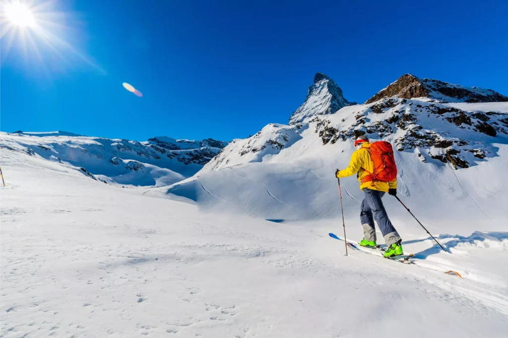 Ski touring with matterhorn in the back Man backcountry skiing on powder snow with Matterhorn in background, Zermatt in Swiss Alps.